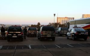 Viaturas da Polícia Militar do Distrito Federal estacionadas ao entardecer com prédios de Brasília ao fundo