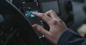 Mão de motorista tocando a tela de um celular preso ao painel do carro