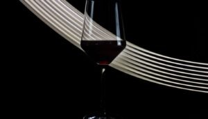 Taça de vinho tinto sobre fundo escuro com faixa de luz