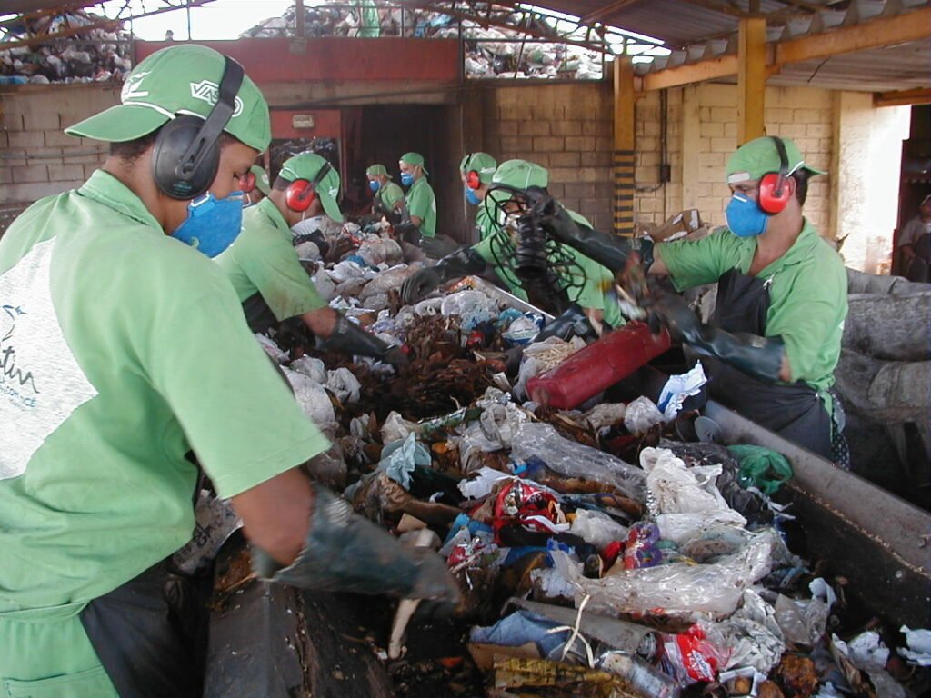 Trabalhadores fazem triagem de material reciclável em esteira