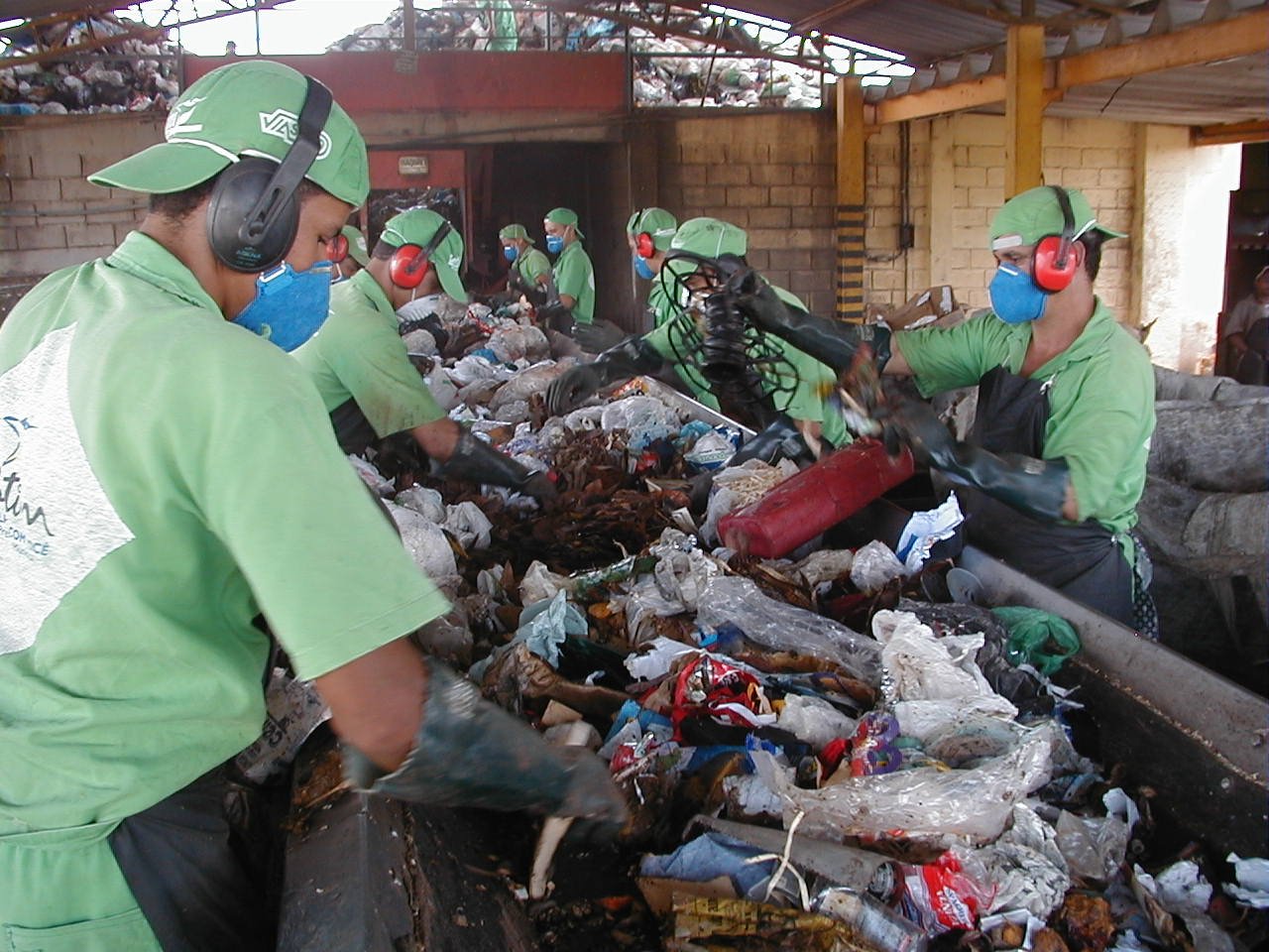 Trabalhadores fazem triagem de material reciclável em esteira