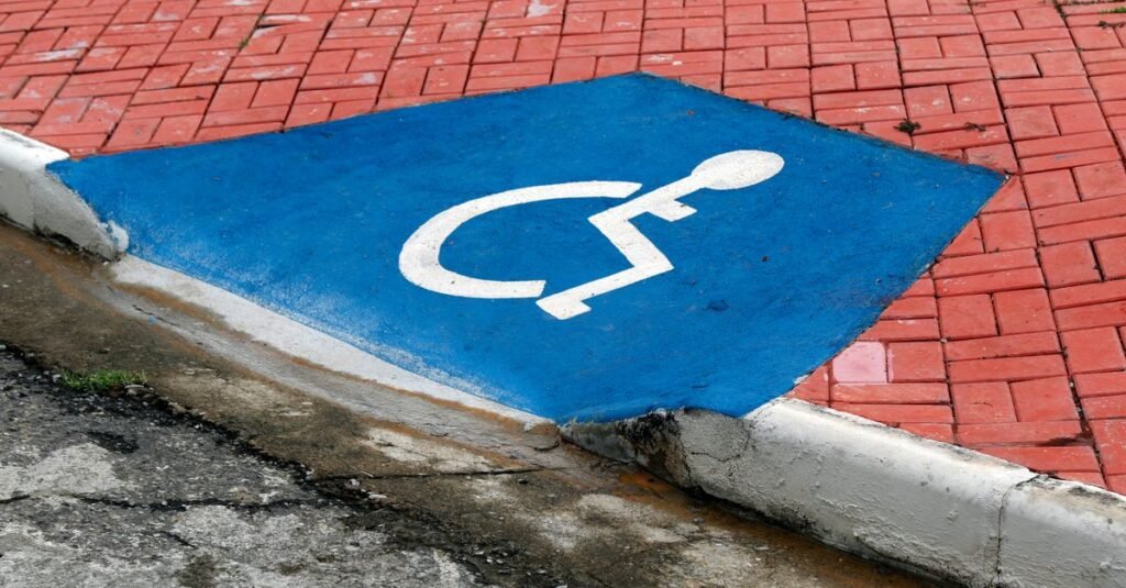 Rampa de acessibilidade em calçada com símbolo internacional de acesso pintado em azul