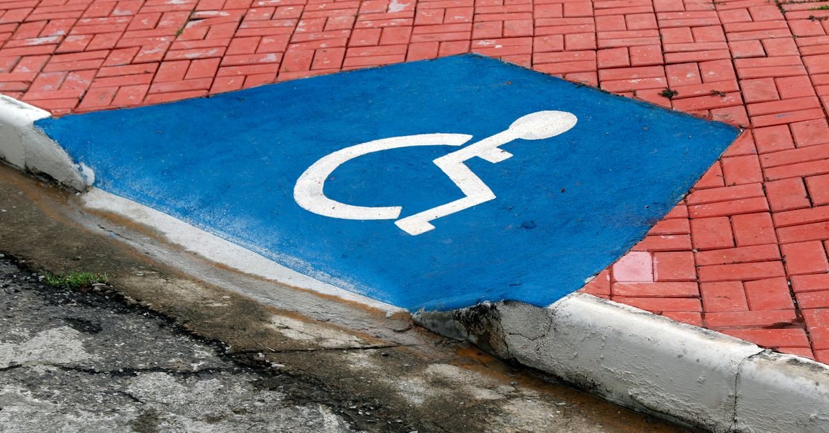 Rampa de acessibilidade em calçada com símbolo internacional de acesso pintado em azul