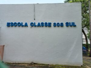 Muro branco de escola publica com as letras azuis Escola Classe 308 Sul, em Brasilia