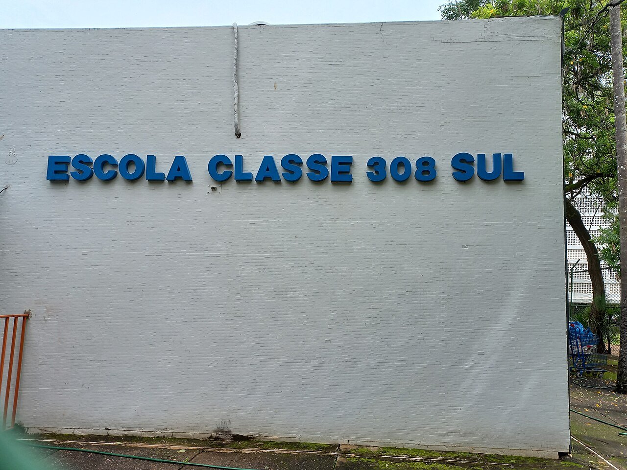 Muro branco de escola publica com as letras azuis Escola Classe 308 Sul, em Brasilia