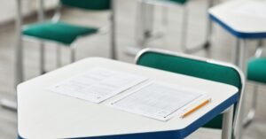 Carteira escolar com folha de respostas e lápis em sala de prova