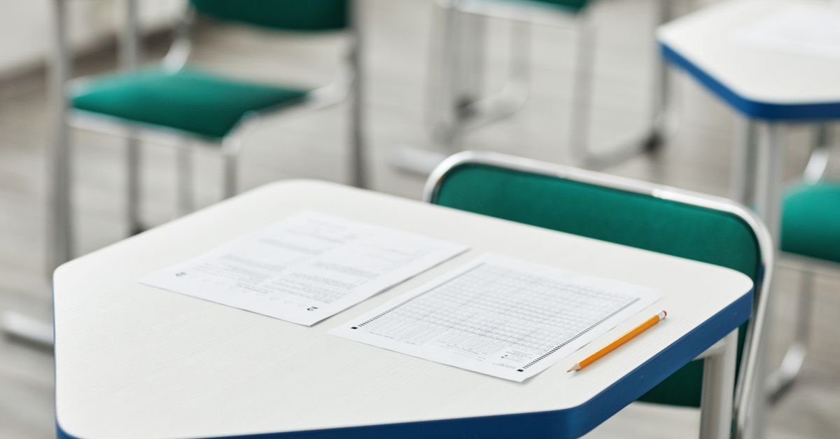 Carteira escolar com folha de respostas e lápis em sala de prova