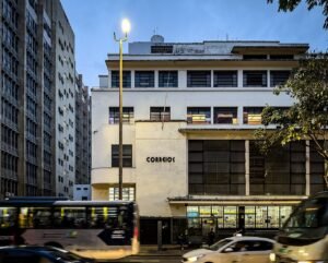 Fachada de agência dos Correios com o letreiro da empresa no fim da tarde