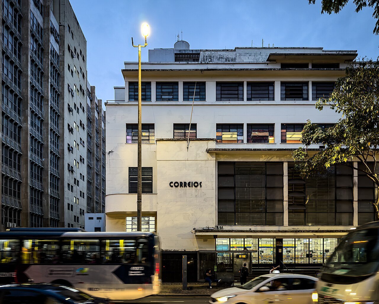 Fachada de agência dos Correios com o letreiro da empresa no fim da tarde