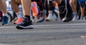 Pés de corredores com tênis esportivos em prova de rua no asfalto
