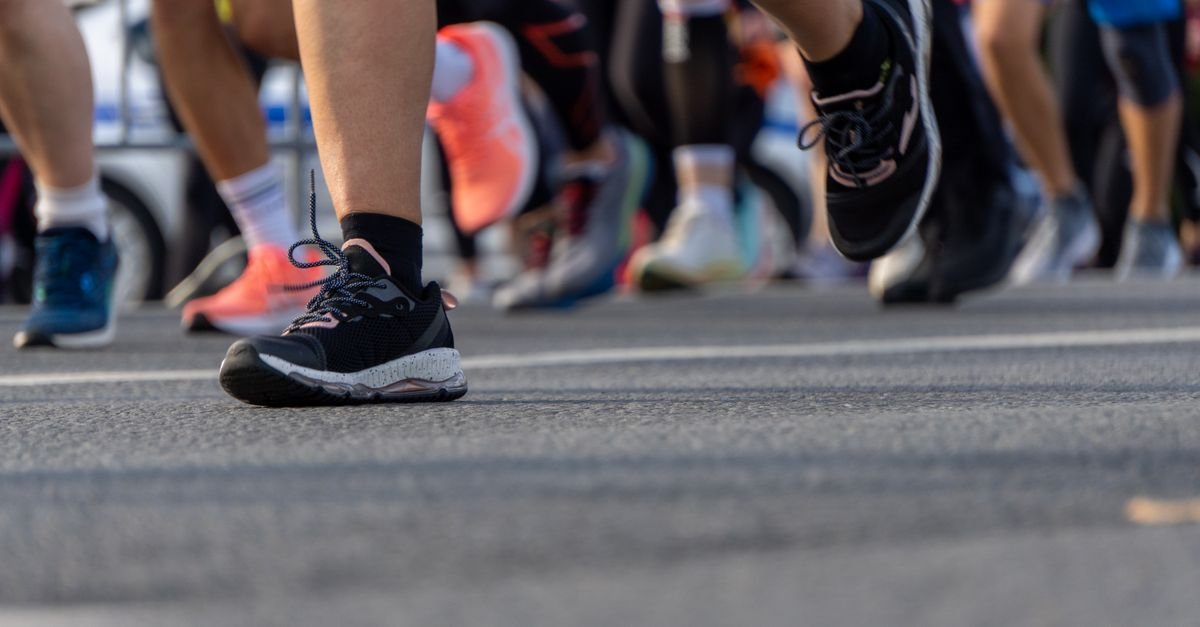 Pés de corredores com tênis esportivos em prova de rua no asfalto