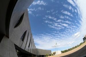 Edifício sede do Superior Tribunal de Justiça, em Brasília, visto de baixo com a bandeira do Brasil ao fundo