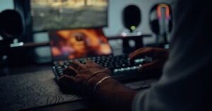 Mãos digitando em teclado de computador em ambiente escuro