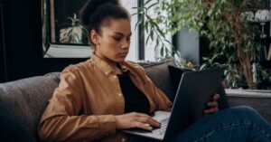 Mulher usa notebook em casa para acessar serviço online