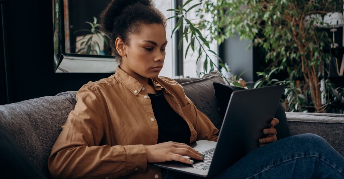 Mulher usa notebook em casa para acessar serviço online