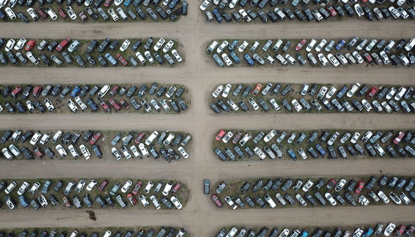 Vista aérea de pátio com centenas de veículos estacionados em fileiras separadas por corredores de terra