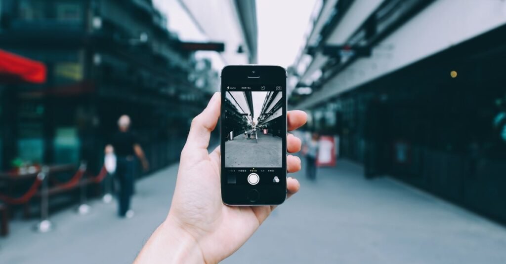 Mão segura celular fotografando uma rua urbana
