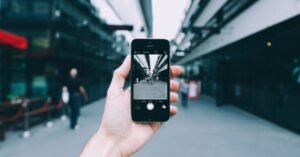 Mão segura celular fotografando uma rua urbana