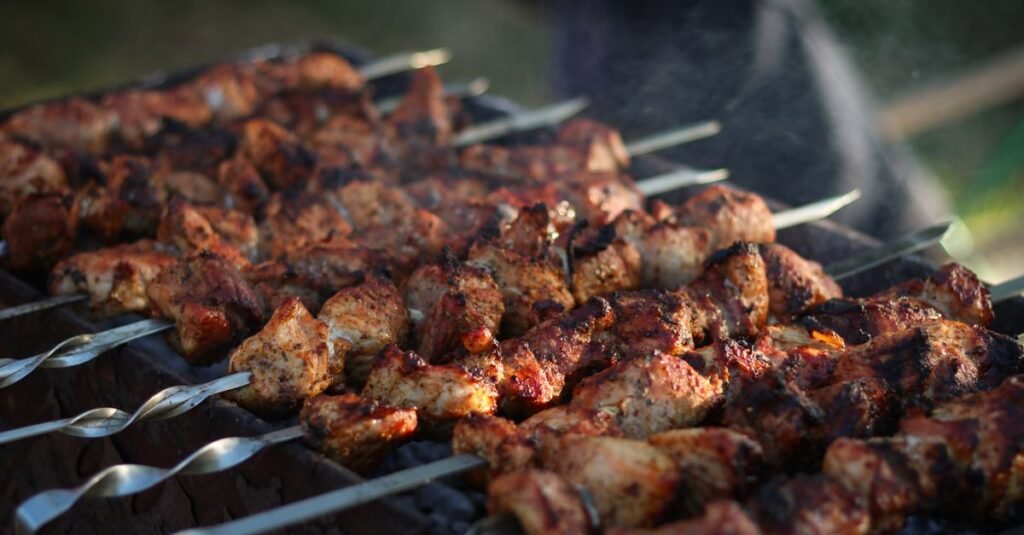 Espetos de carne assando sobre a brasa em churrasqueira ao ar livre