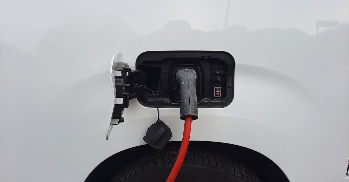 Cabo de recarga vermelho conectado à porta de carregamento de um carro elétrico branco