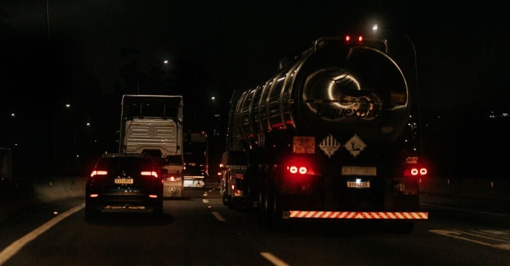 Veículos de carga trafegam em rodovia à noite, iluminados pelas lanternas traseiras