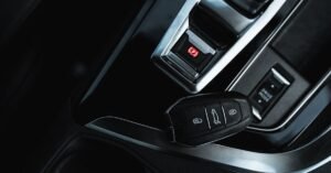 Chave de carro sobre o console central de um veículo, ao lado do botão de freio de estacionamento eletrônico
