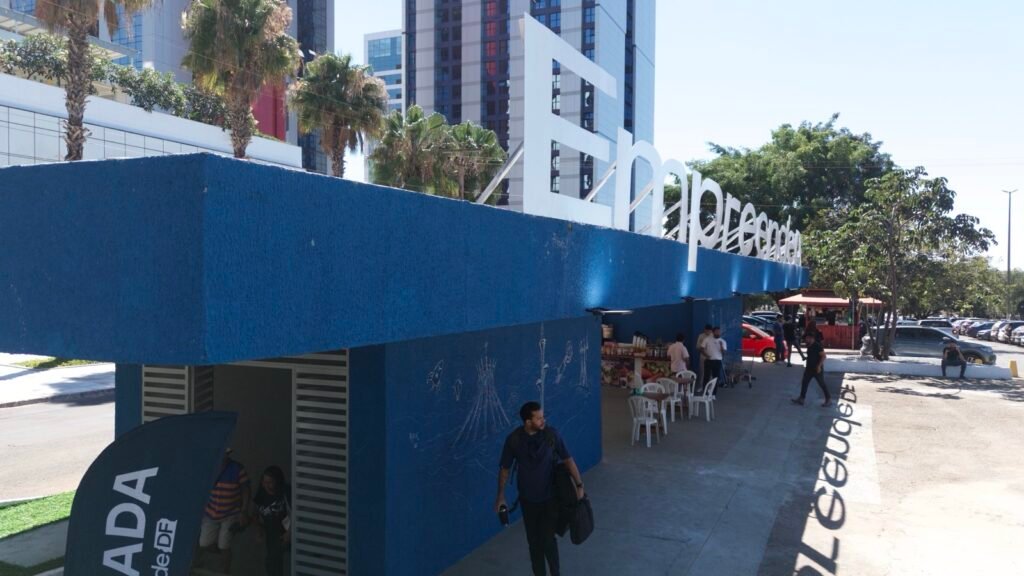 Fachada do hub EmpreendeDF em Brasília, com letreiro branco sobre estrutura azul e pessoas circulando