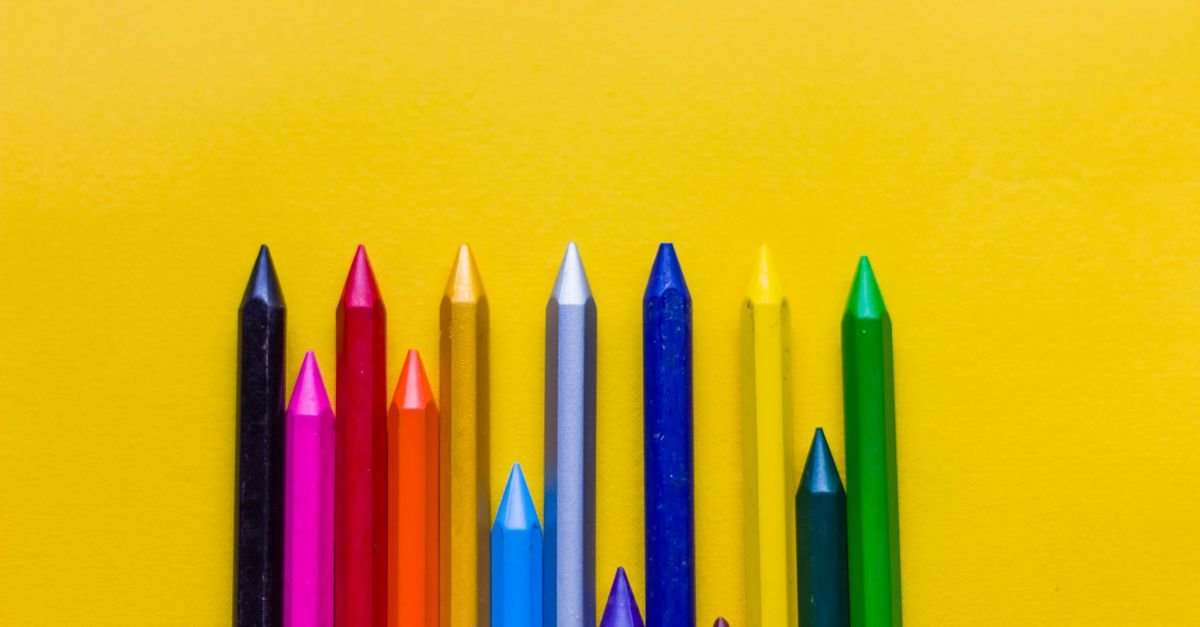 Gizes de cera coloridos alinhados lado a lado sobre fundo amarelo