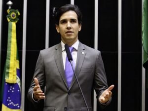 O deputado federal Euclydes Pettersen discursa na tribuna do plenário da Câmara dos Deputados, ao lado da bandeira do Brasil