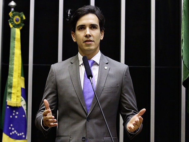 O deputado federal Euclydes Pettersen discursa na tribuna do plenário da Câmara dos Deputados, ao lado da bandeira do Brasil