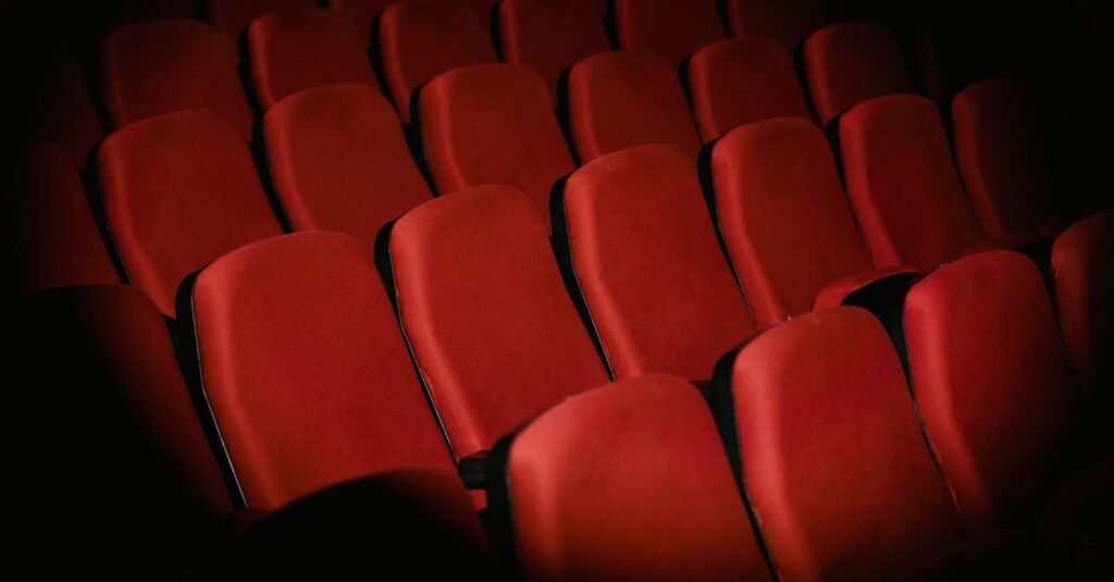 Fileiras de poltronas vermelhas vazias em uma sala de teatro