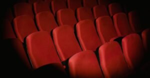 Fileiras de poltronas vermelhas vazias em uma sala de teatro