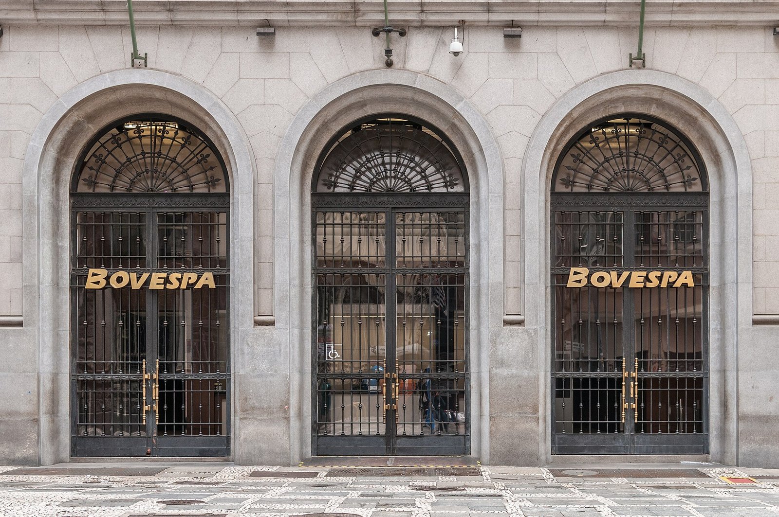 Fachada de pedra do prédio da Bovespa, no centro de São Paulo, com portas em arco e letreiro dourado