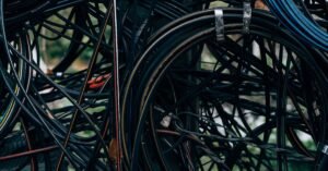 Emaranhado de cabos elétricos e de telecomunicação presos em poste, em close