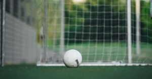 Bola de futebol parada na linha do gol em campo de grama