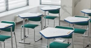 Carteiras escolares vazias com folhas de prova e lápis sobre as mesas