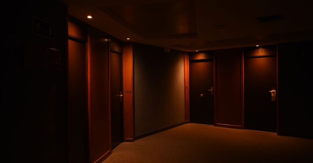 Corredor de hotel com portas de madeira fechadas e iluminação baixa