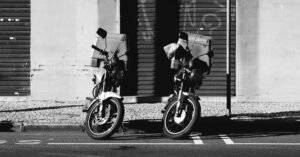Duas motocicletas estacionadas junto ao meio-fio em rua urbana