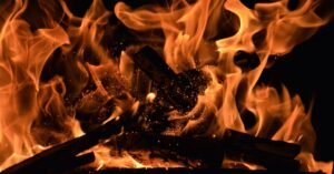 Chamas altas e brasas incandescentes queimando madeira contra fundo escuro
