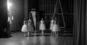 Bailarinas aguardam nos bastidores de um teatro antes de entrar em cena