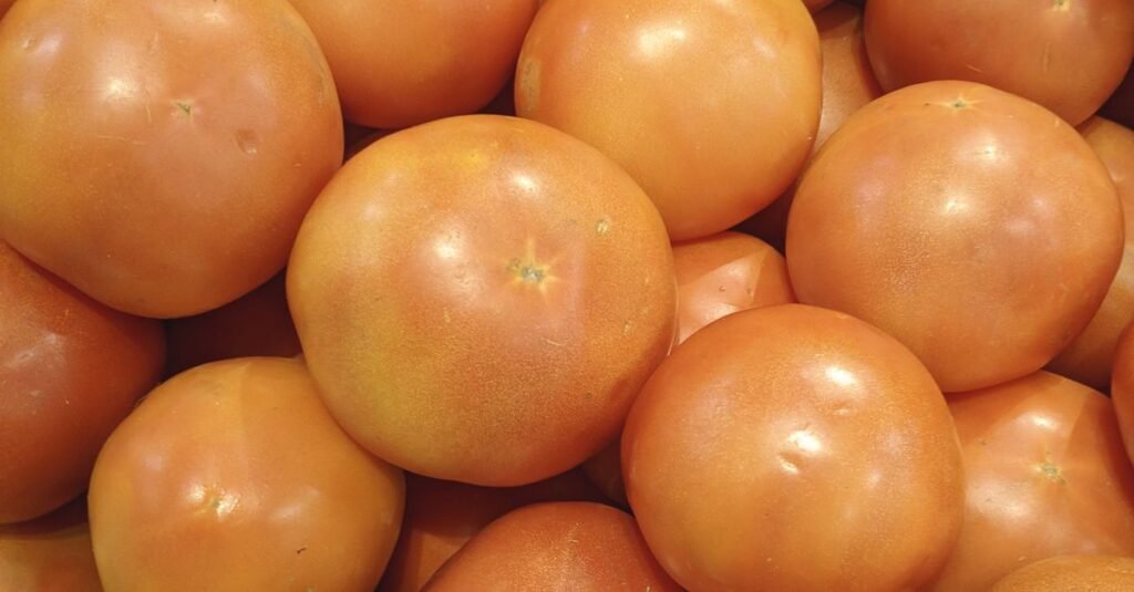 Tomates maduros amontoados em uma banca de feira, vistos de perto