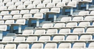 Arquibancada de estádio com fileiras de cadeiras brancas vazias