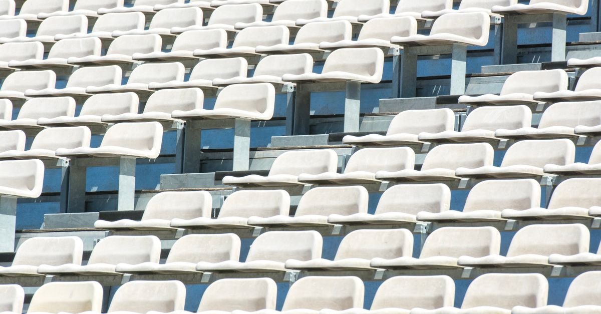 Arquibancada de estádio com fileiras de cadeiras brancas vazias