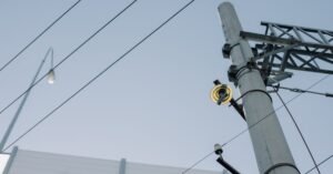 Poste de concreto com isolador amarelo e fios da rede elétrica contra o céu limpo