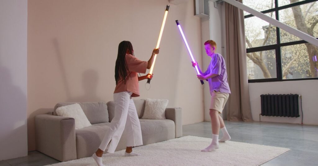 Duas pessoas empunham sabres de luz de LED, um laranja e um roxo, em uma sala