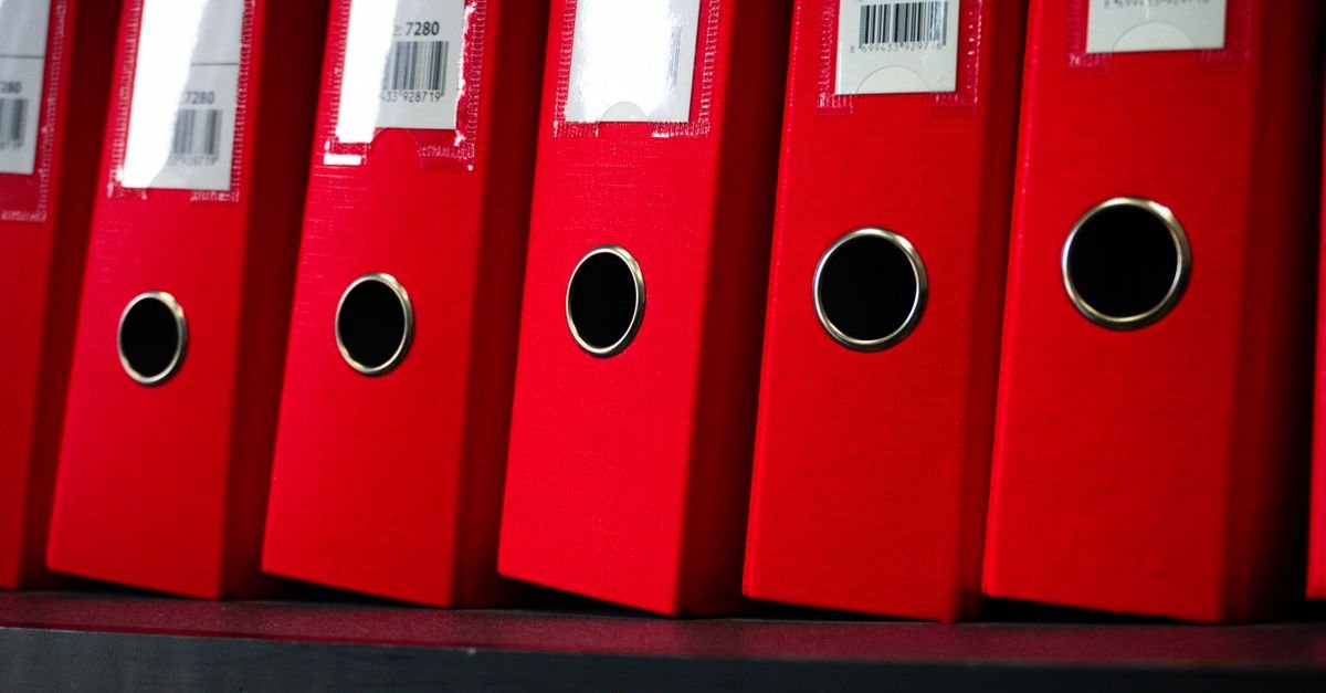 Pastas de arquivo vermelhas enfileiradas em uma estante