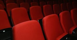 Fileiras de poltronas vermelhas vazias em sala de cinema