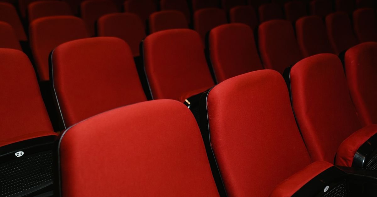 Fileiras de poltronas vermelhas vazias em sala de cinema