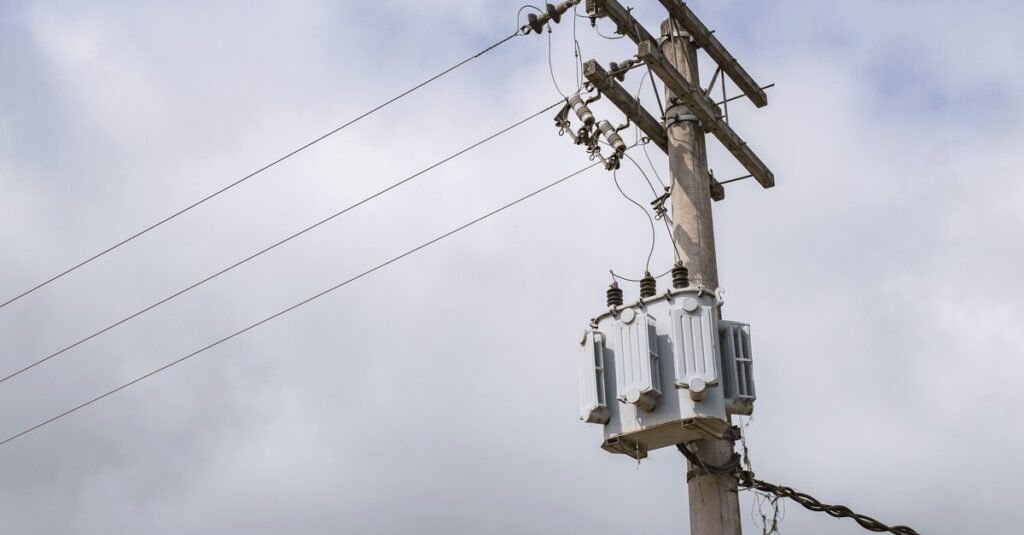 Transformador instalado em poste de rede elétrica com céu nublado ao fundo