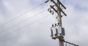 Transformador instalado em poste de rede elétrica com céu nublado ao fundo